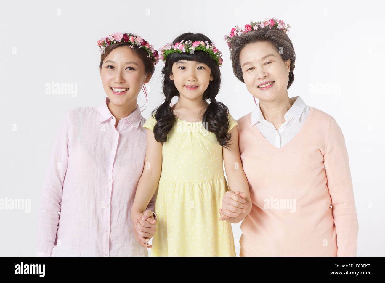 Young girl, young adult woman, senior woman together all wearing flower crowns and staring forward with a smile with their Stock Photo
