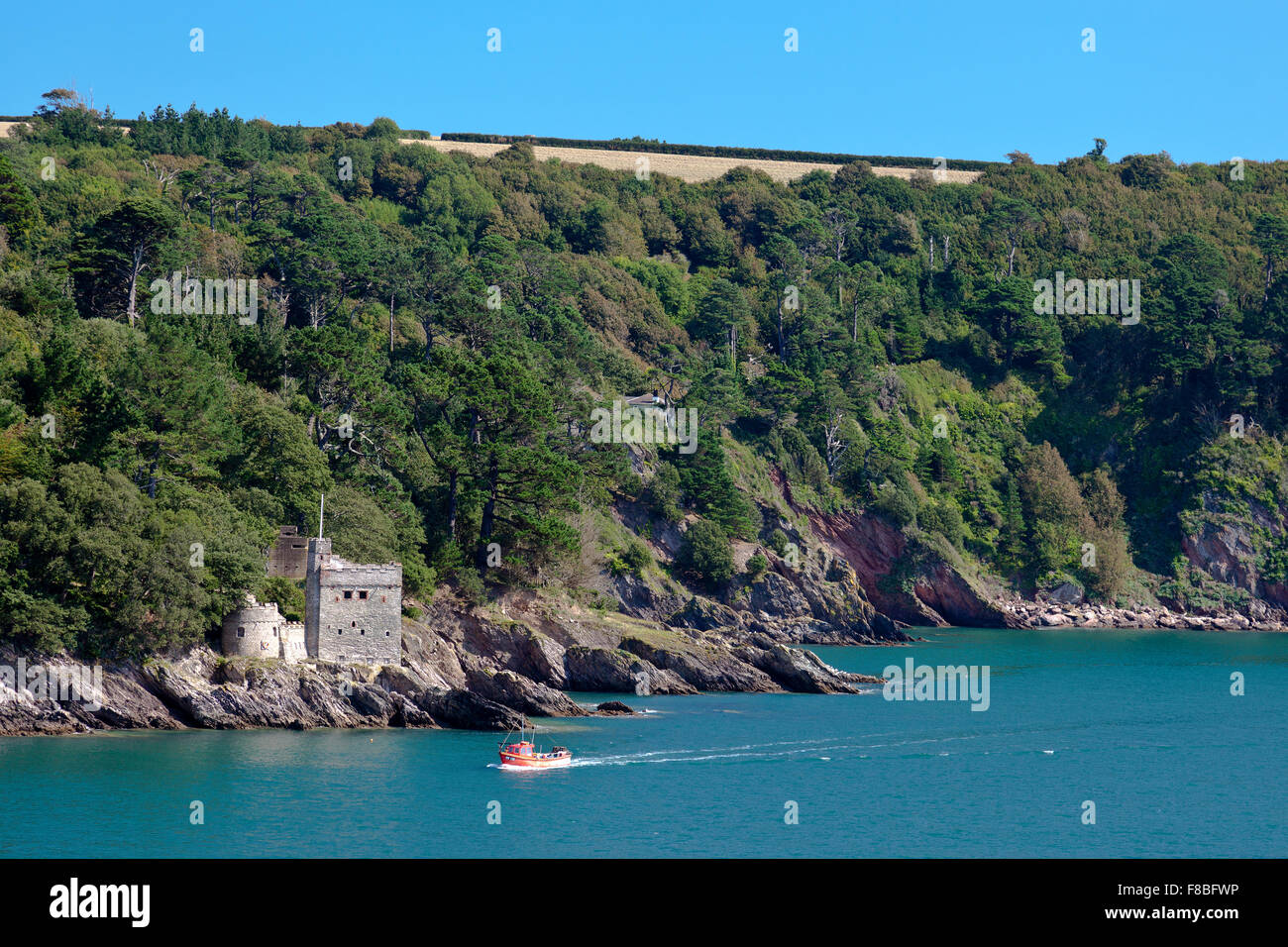A small fishing boat passes Kingswear Castle at the mouth of the River Dart, Devon, England, UK Stock Photo