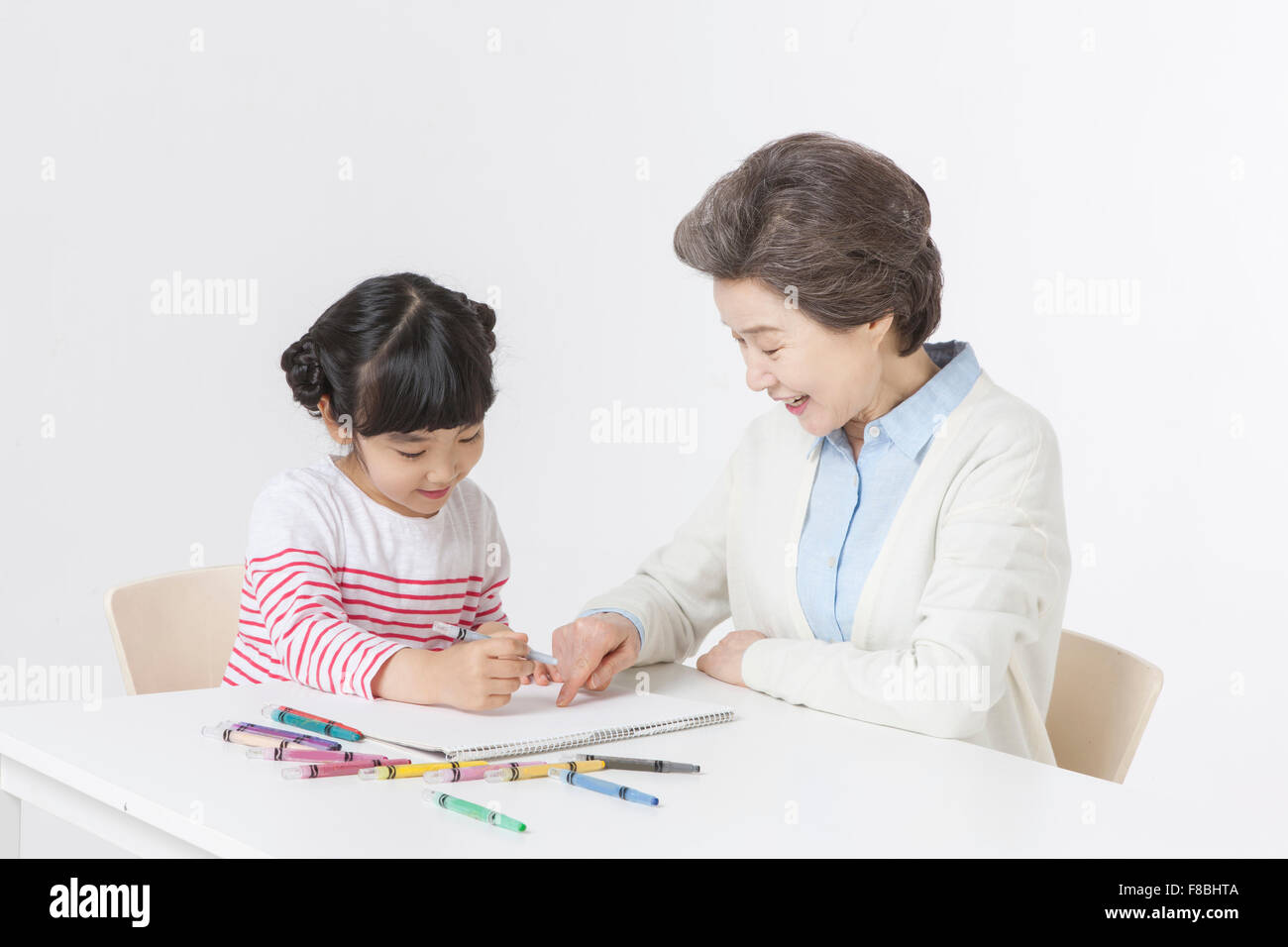 https://c8.alamy.com/comp/F8BHTA/young-girl-drawing-on-sketch-pad-with-color-pencils-and-her-grandmother-F8BHTA.jpg