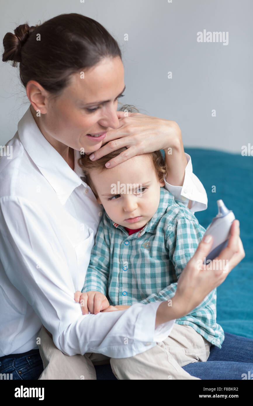Checking the temperature of a 2 year-old boy with ear thermometer. Stock Photo