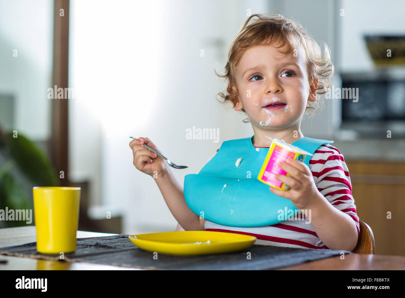 2 year-old boy eating a yoghurt. Stock Photo