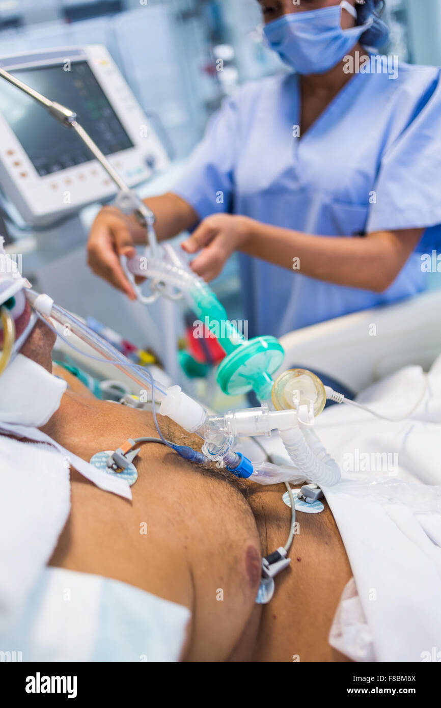 Nurse with a patient under respiratory assistance. Intensive care department. Stock Photo