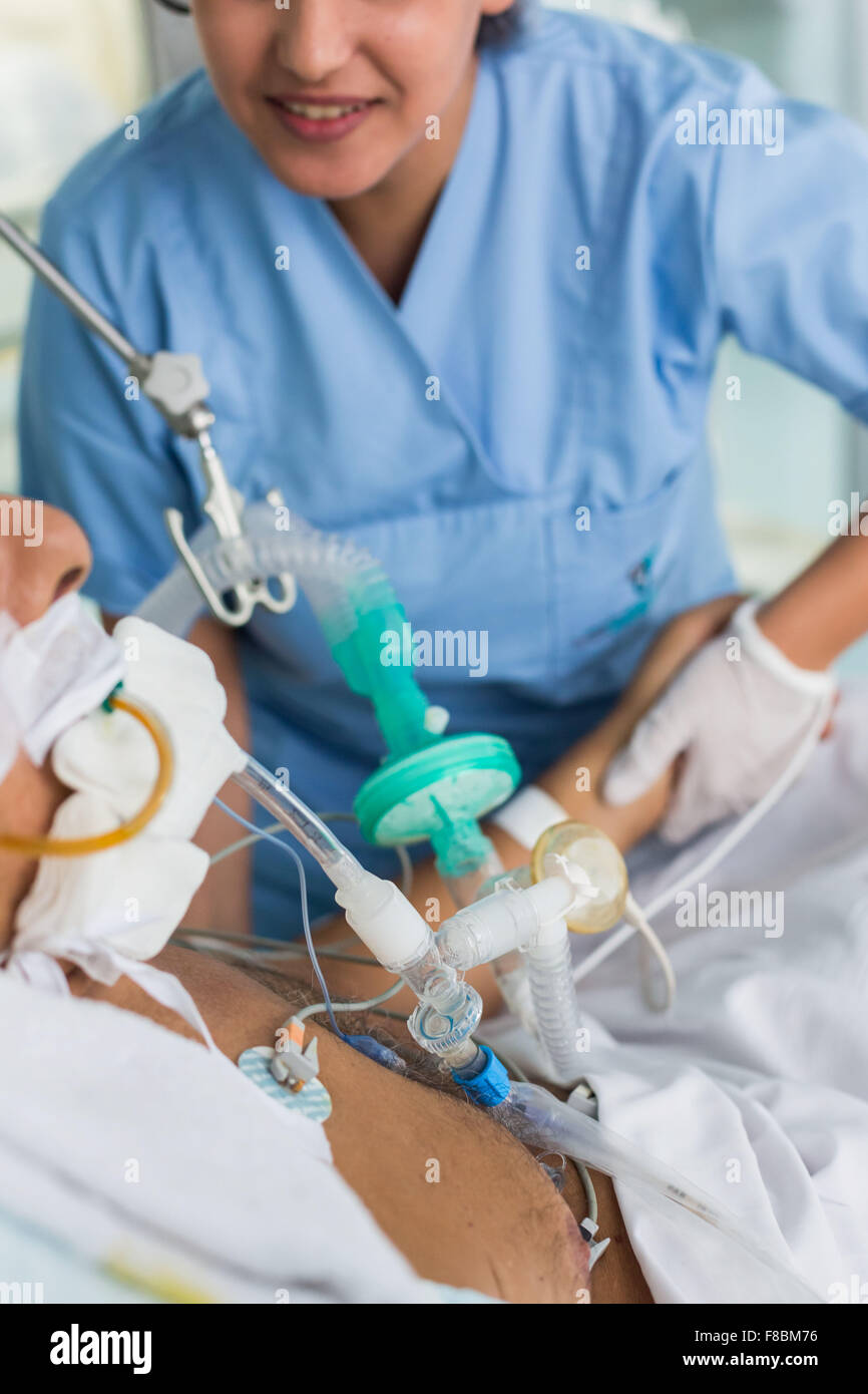 Nurse with a patient under respiratory assistance. Intensive care department. Stock Photo