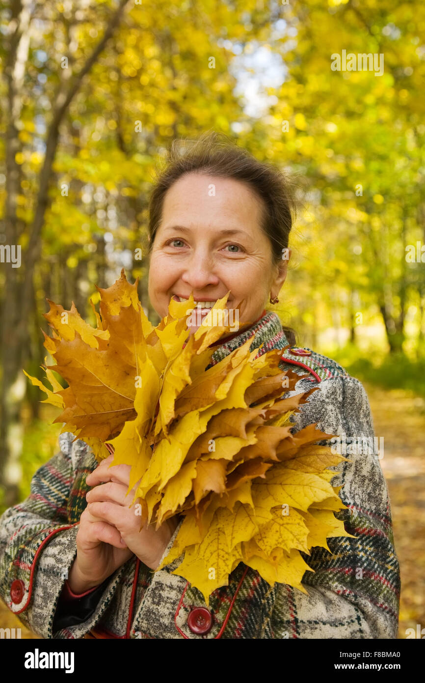 Portrait of senior woman with maple leaves in autumn park Stock Photo ...