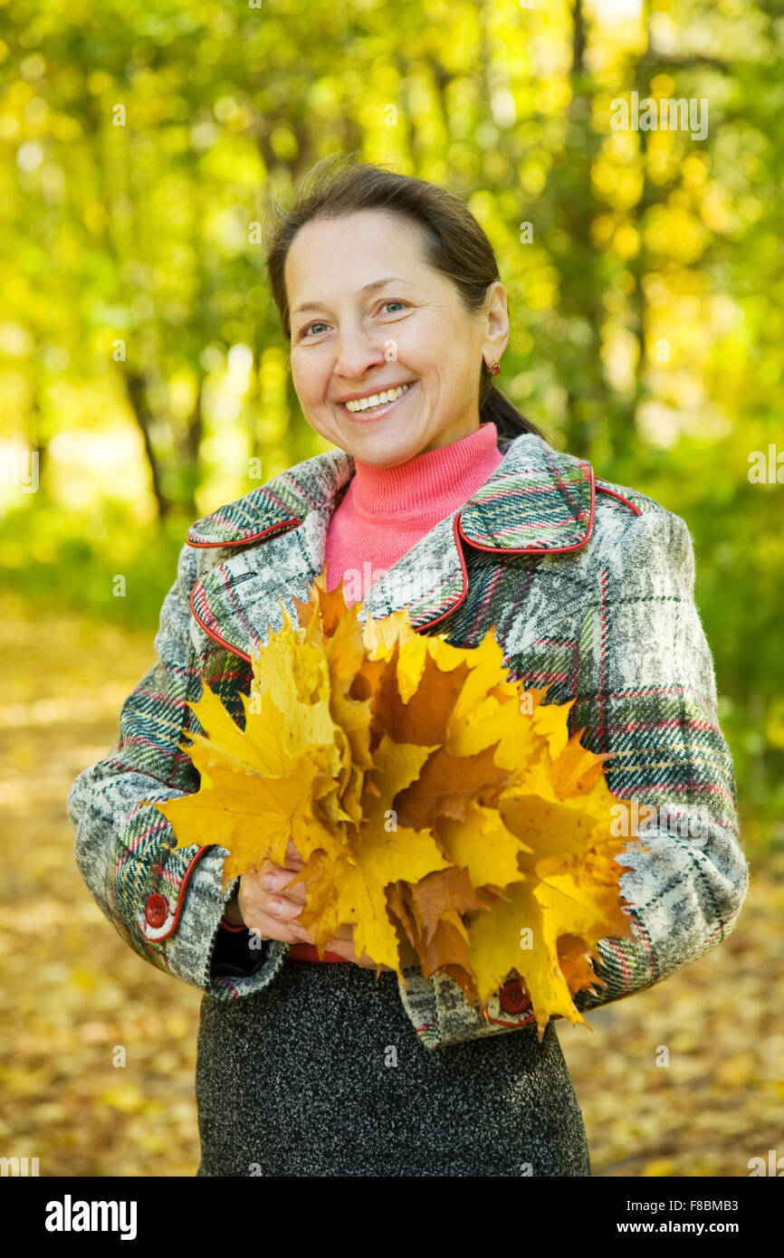 Portrait of mature woman with maple leaves in autumn park Stock Photo ...