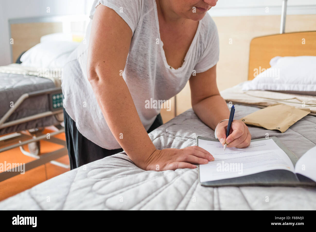 Female patient signing medical forms before surgery. Stock Photo