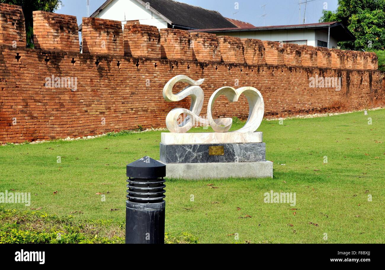 Kanchanaburi, Thailand:  Contemporary sculpture in front of a surviving portion of the old brick crenelated defense wall Stock Photo