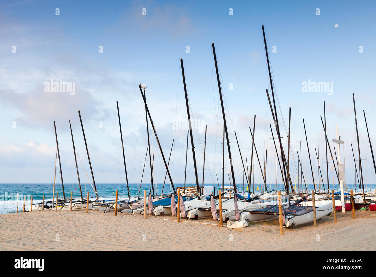 Sailing boats lay in a row on the sandy beach in Calafell, coast of Mediterranean sea, Spain Stock Photo