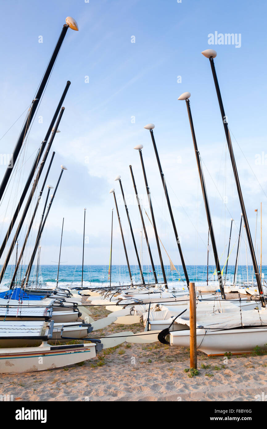 Sailing boats lay on the sandy beach in Calafell, coast of Mediterranean sea, Catalonia, Spain Stock Photo