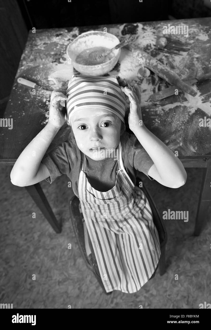 little chef in the kitchen wearing an apron and headscarf Stock Photo