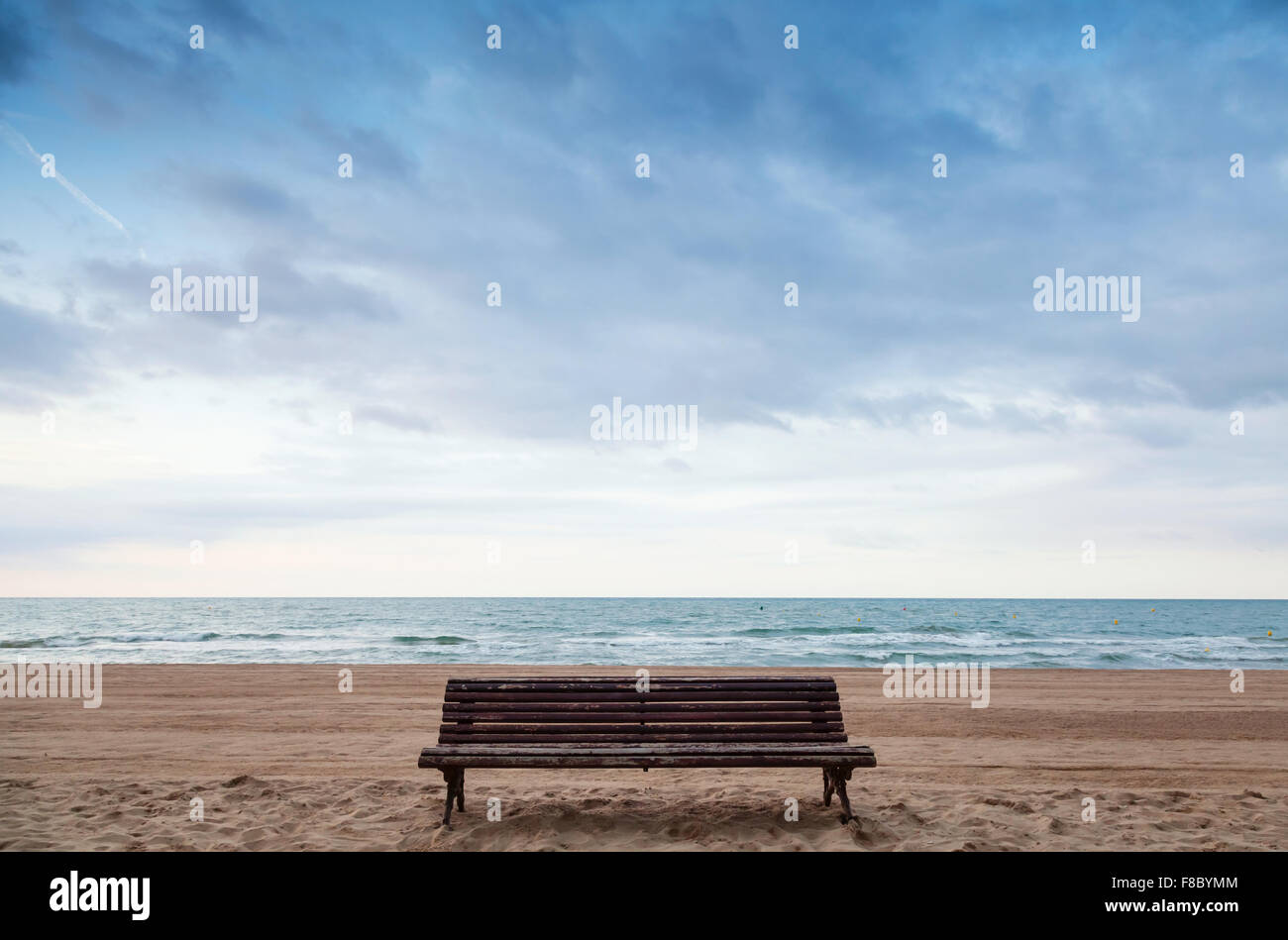 Old empty bench stands on sandy beach, Mediterranean sea coast, Spain Stock Photo