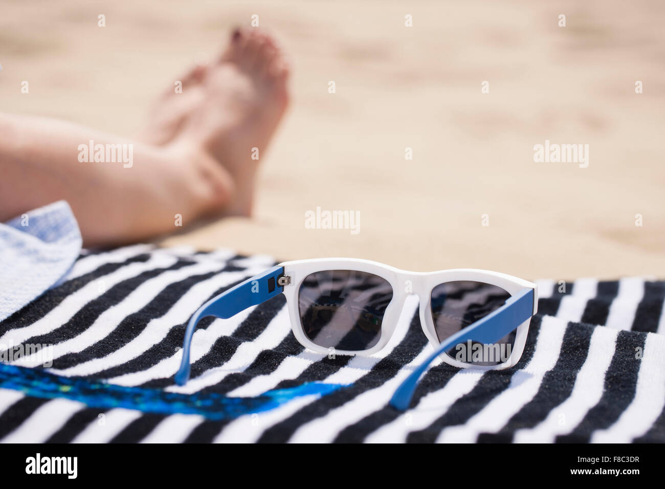 sunglasses on towel out of focus on sand Stock Photo