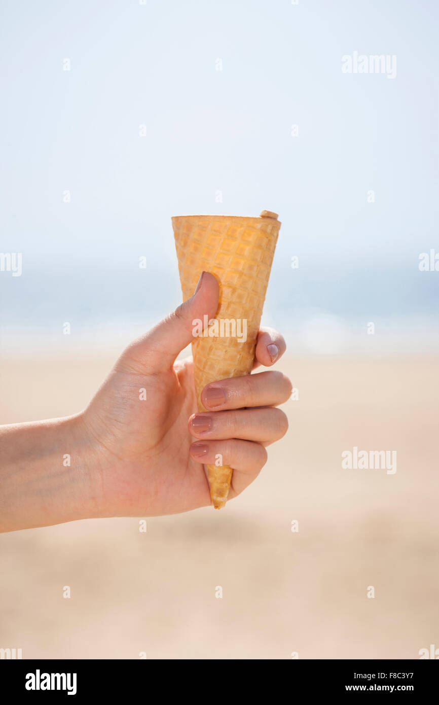 Ice cream cone without ice cream held by a hand in outfocused effect