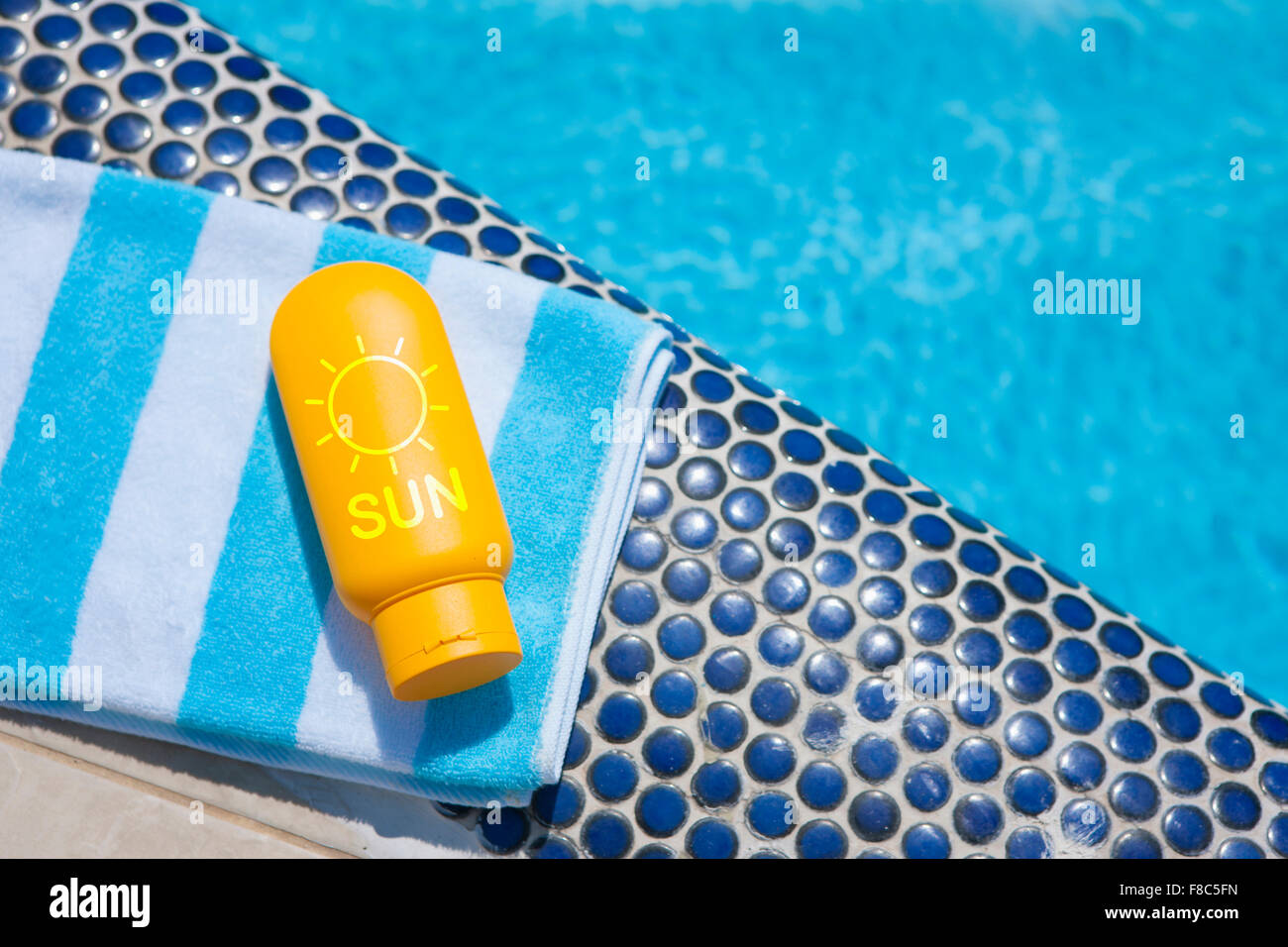 Sunscreen on folded towel with the background of swimming pool Stock