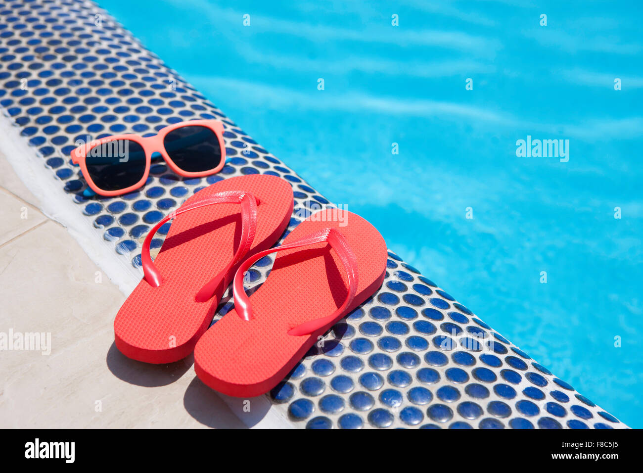 Sunglasses and flip-flops at the edge of the swimming pool Stock Photo ...