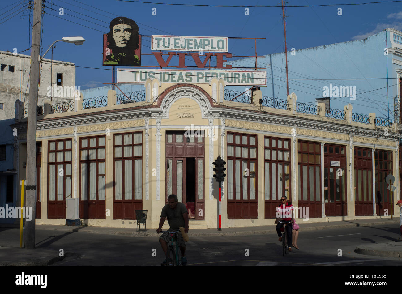 A bicycle passes a street corner in Cienfuegos with a image of Che Guevara and the quote 'your example lives, your ideas endure' Stock Photo