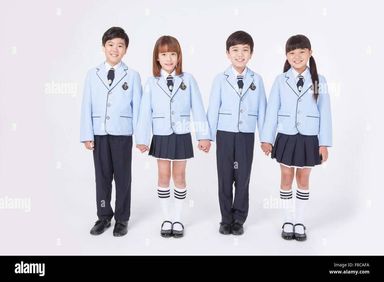 Four elementary school age kids standing and holding each other's hand and smiling Stock Photo