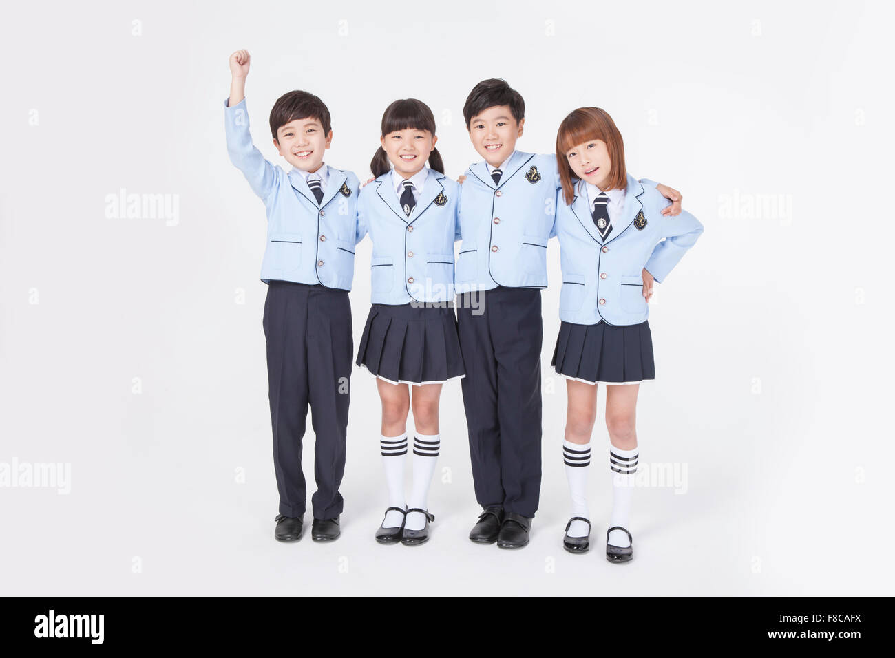 Four elementary school age kids standing together with their arms around each other and smiling Stock Photo