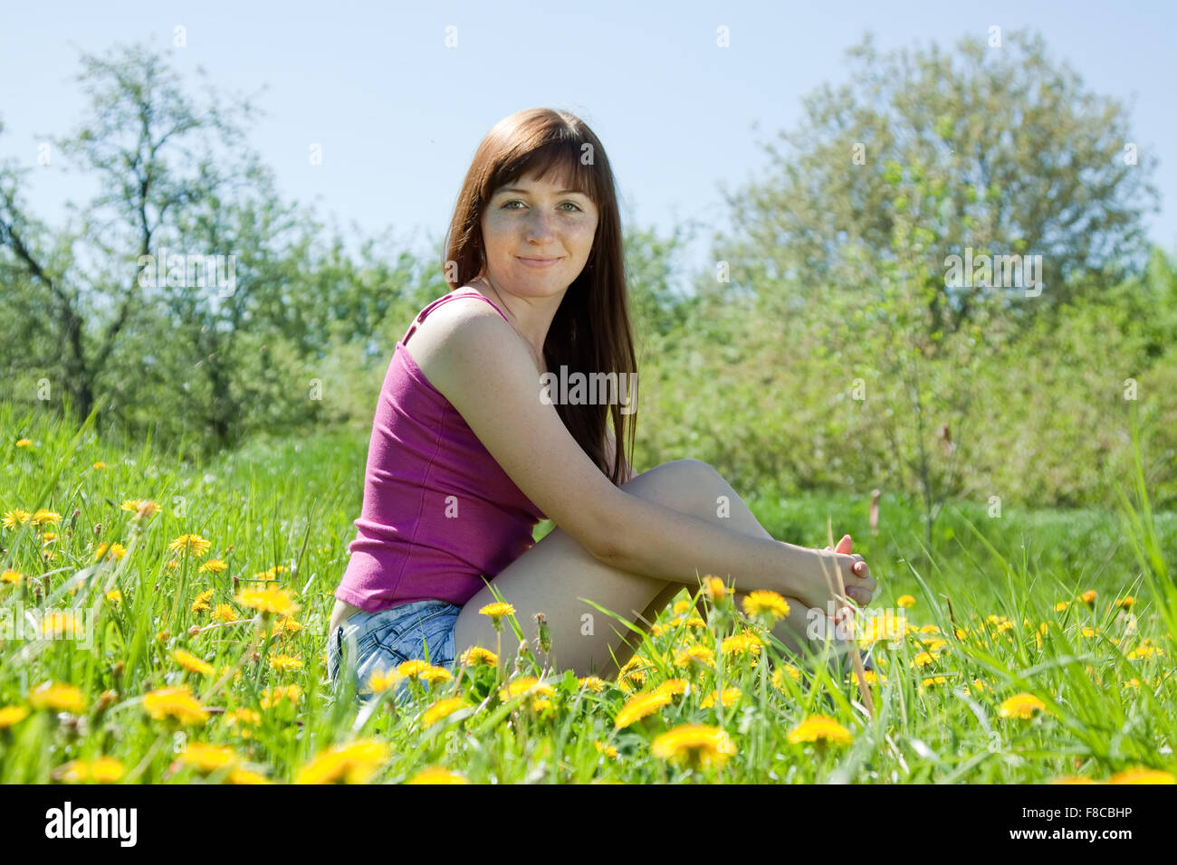 Happy girl sitting outdoor in dandelion meadow Stock Photo - Alamy