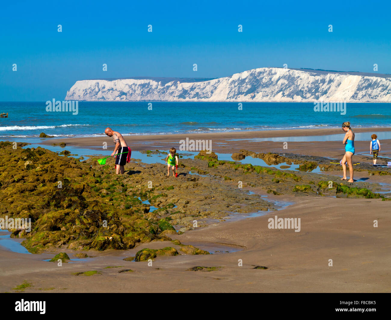 Family on the beach at Compton Bay on the Isle of Wight England UK looking north west towards the chalk cliffs at Tennyson Down Stock Photo