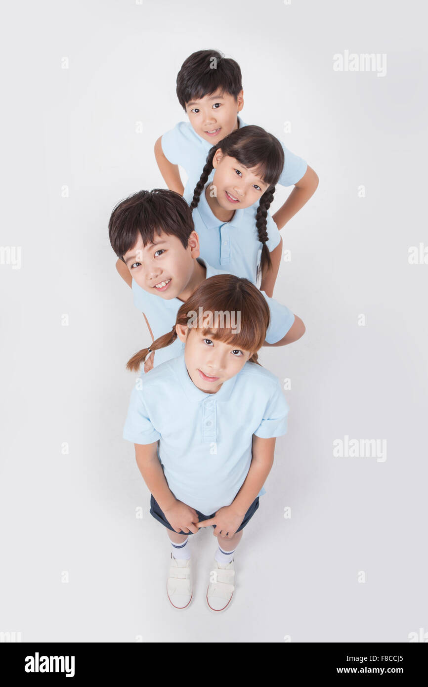 High angle of four elementary school students in sports uniforms lined up with their hands on their waist and tilting their Stock Photo