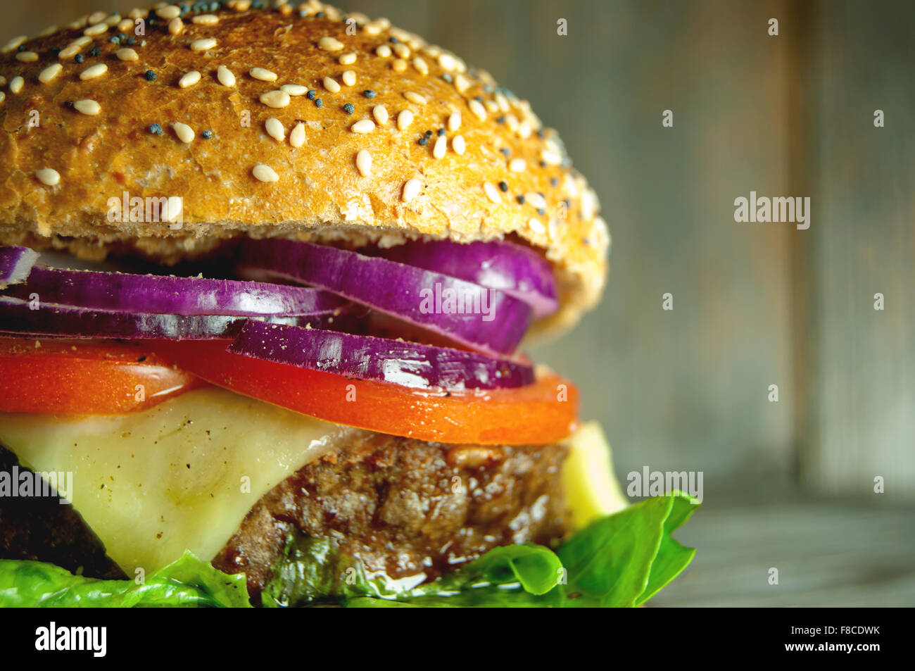Close up of a gourmet burger with cheese, tomato and onion filling Stock Photo