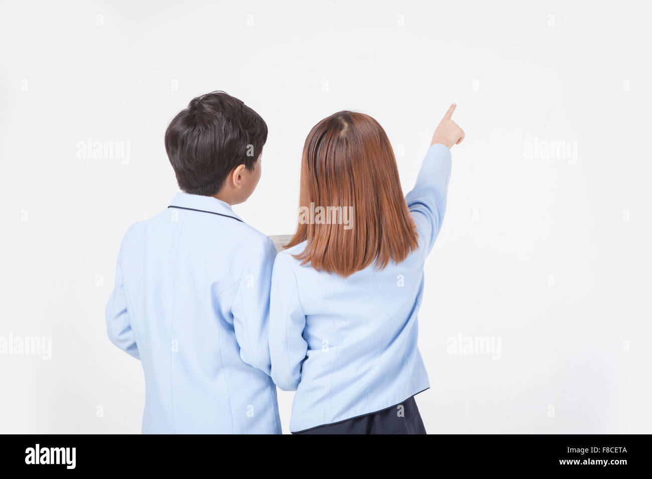 Back appearance of elementary school boy and girl in school uniforms with her finger pointing Stock Photo