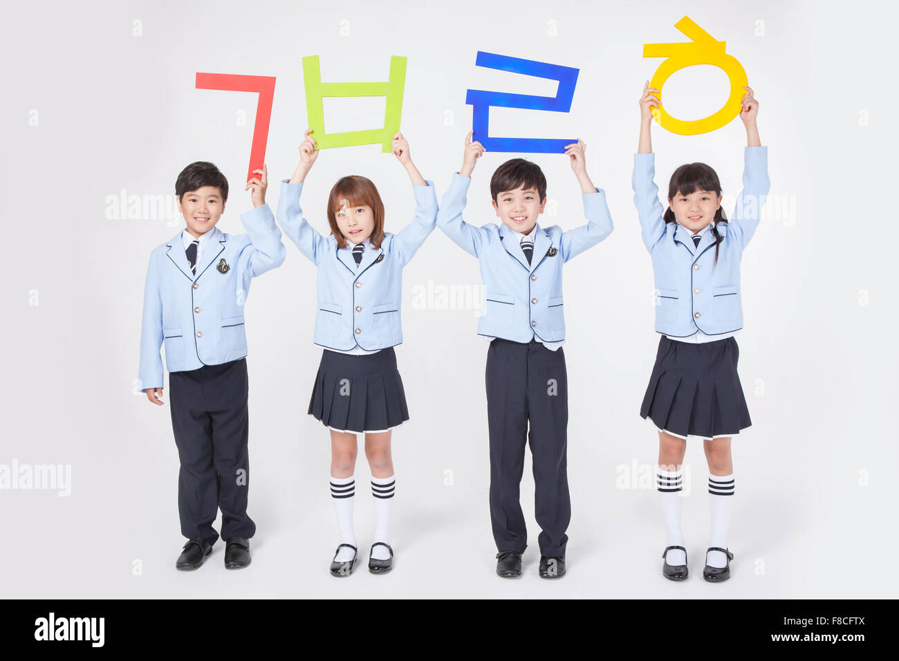Four elementary school students in school uniforms standing and holding  Korean character up high each Stock Photo - Alamy