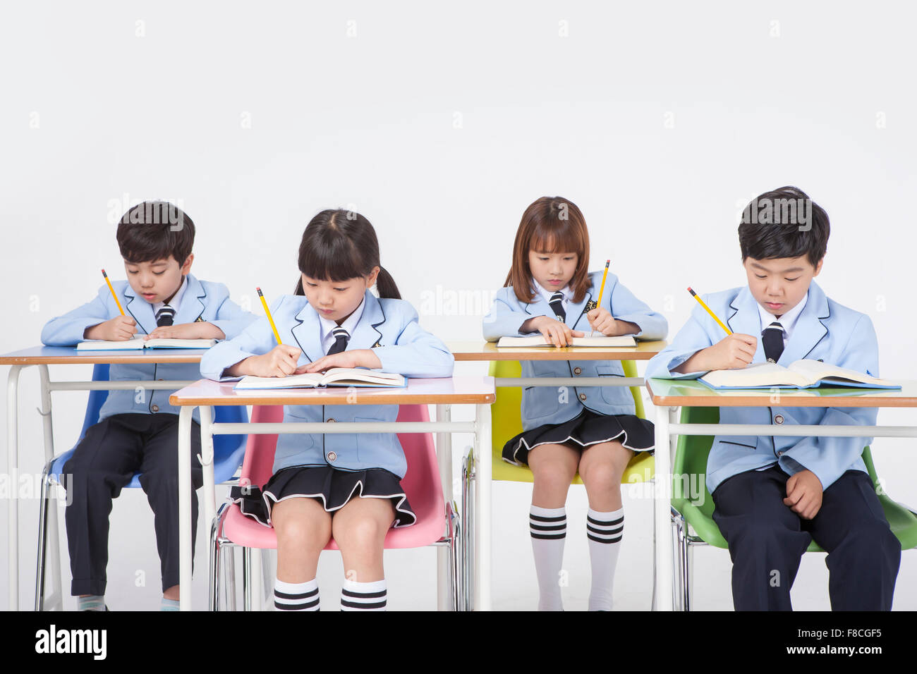 Four Elementary School Students In School Uniforms Seated At Desk