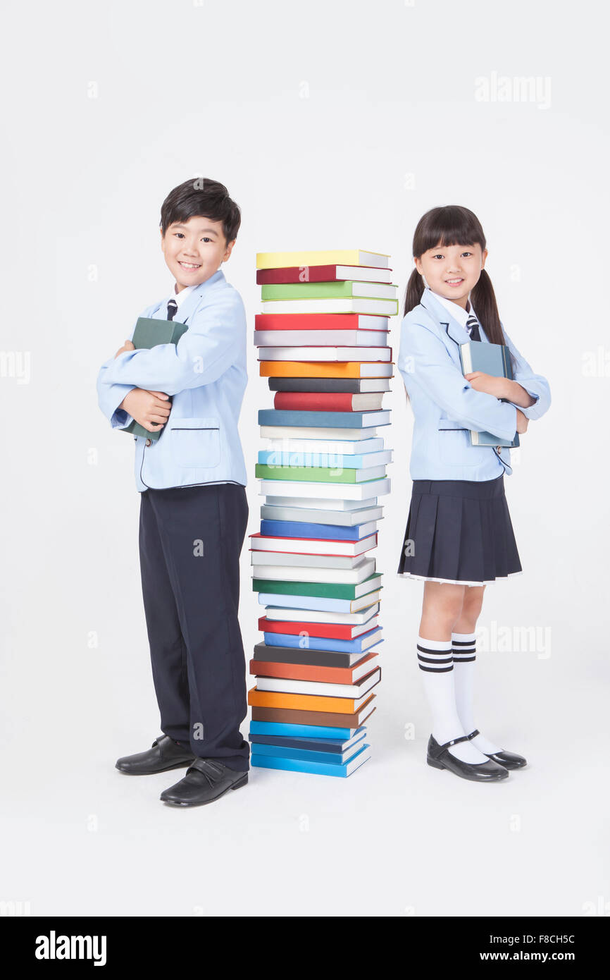 Elementary school boy and girl in school uniforms standing back to back ...