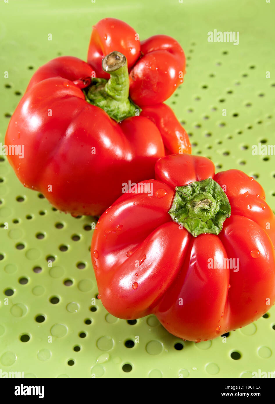 Two red sweet pepper on a green background Stock Photo - Alamy