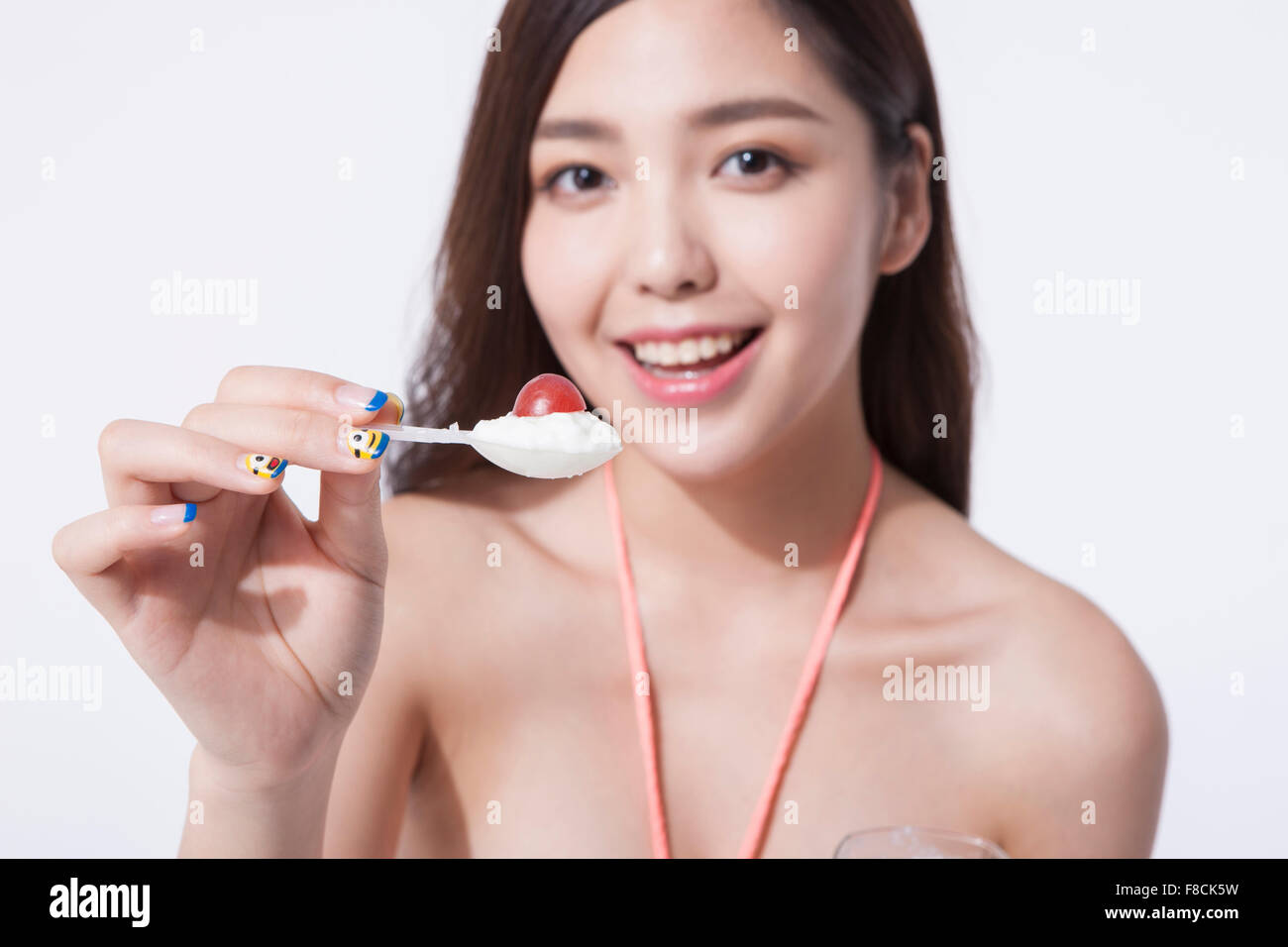 Woman with long hair in bikini holding an yogurt cup and a scoop of