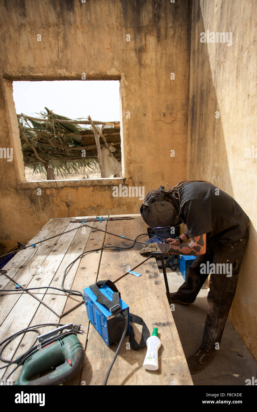 Welder working on metal tubes in the bush in Mali Stock Photo