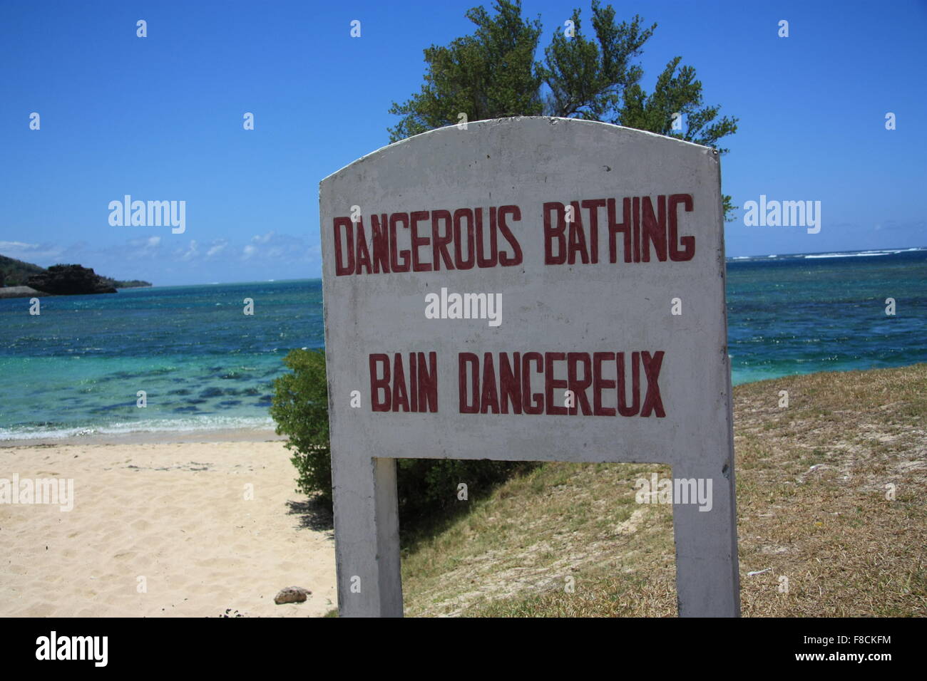 Dangerous Bathing - sign on sandy beach. Southwest Mauritius. Dangerous currents near the coast of Mauritius. Indian Ocean Stock Photo