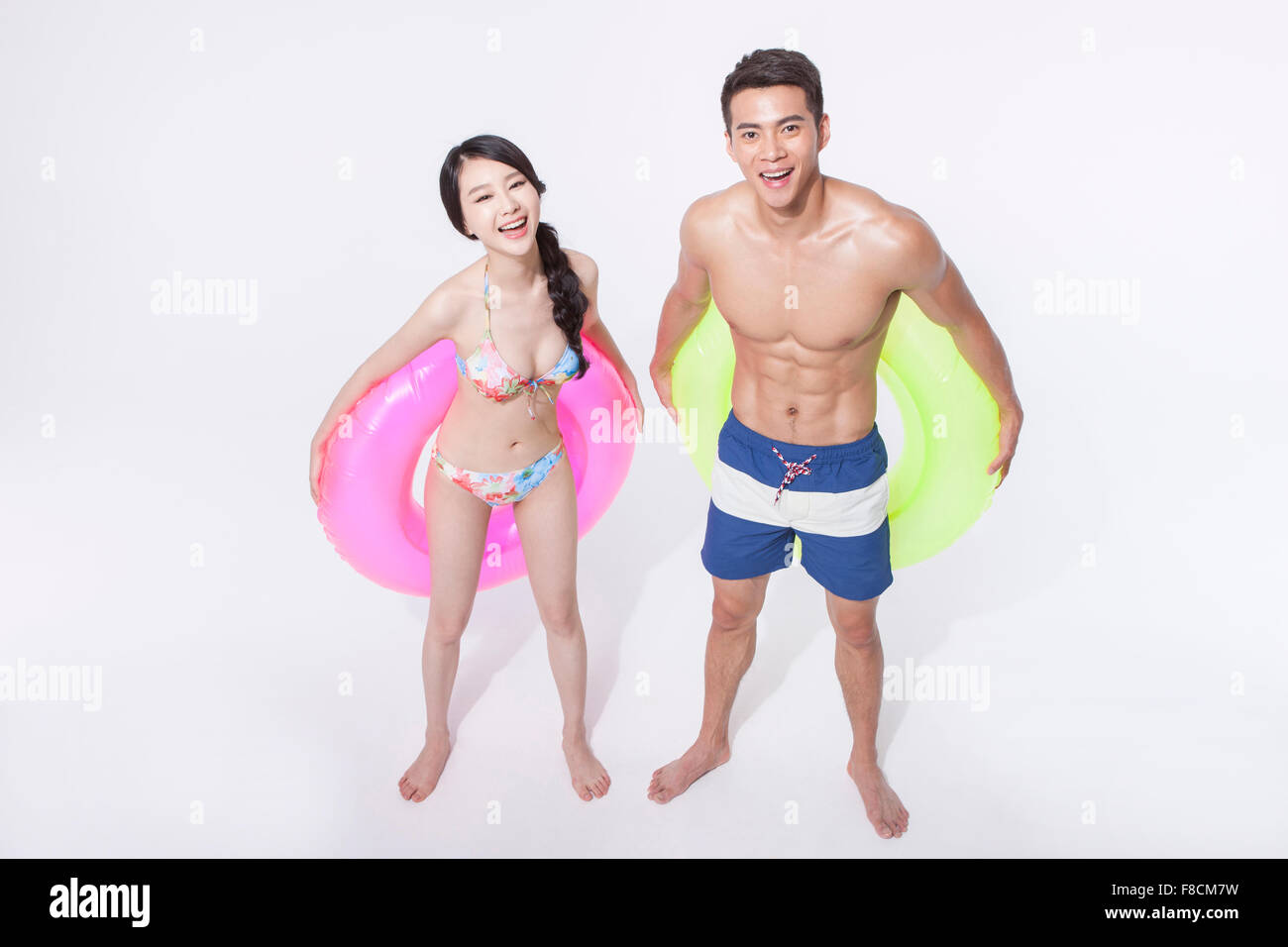 High angle of a couple in beach wear and holding a ring tube behind their back each and smiling Stock Photo