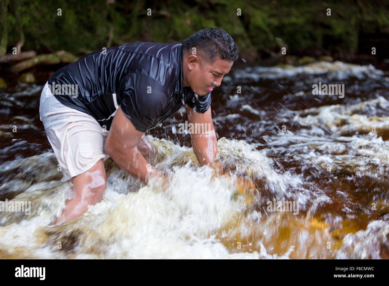 Strong man lifting stones out of the river, Venezuela Stock Photo