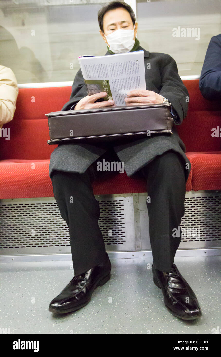 Man reading his newspaper in the Tokyo metro Stock Photo