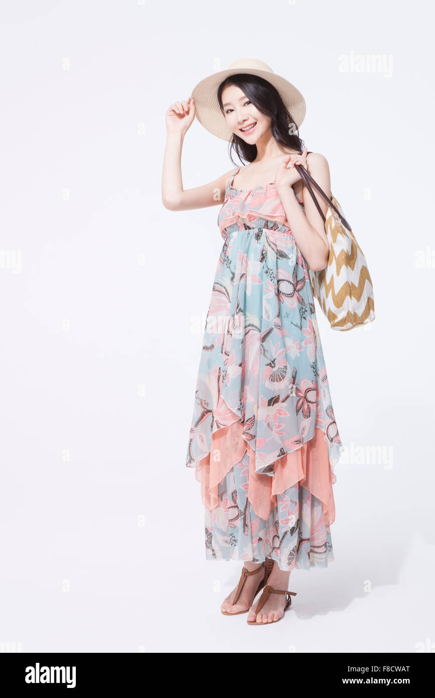 Woman with long hair in maxi dress and a hat standing and holding her ...