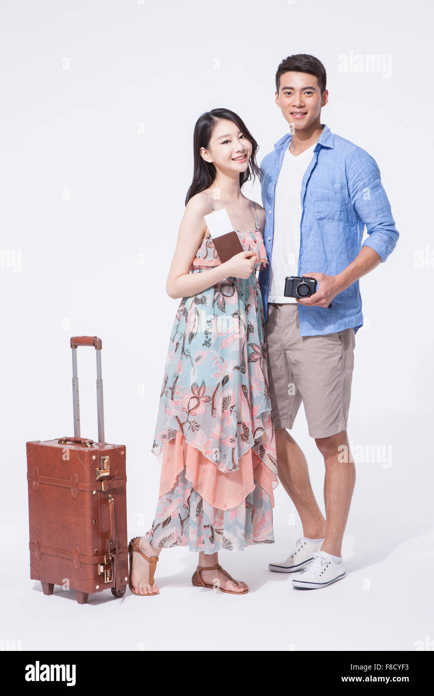 Couple holding passport with flight tickets and a camera each standing