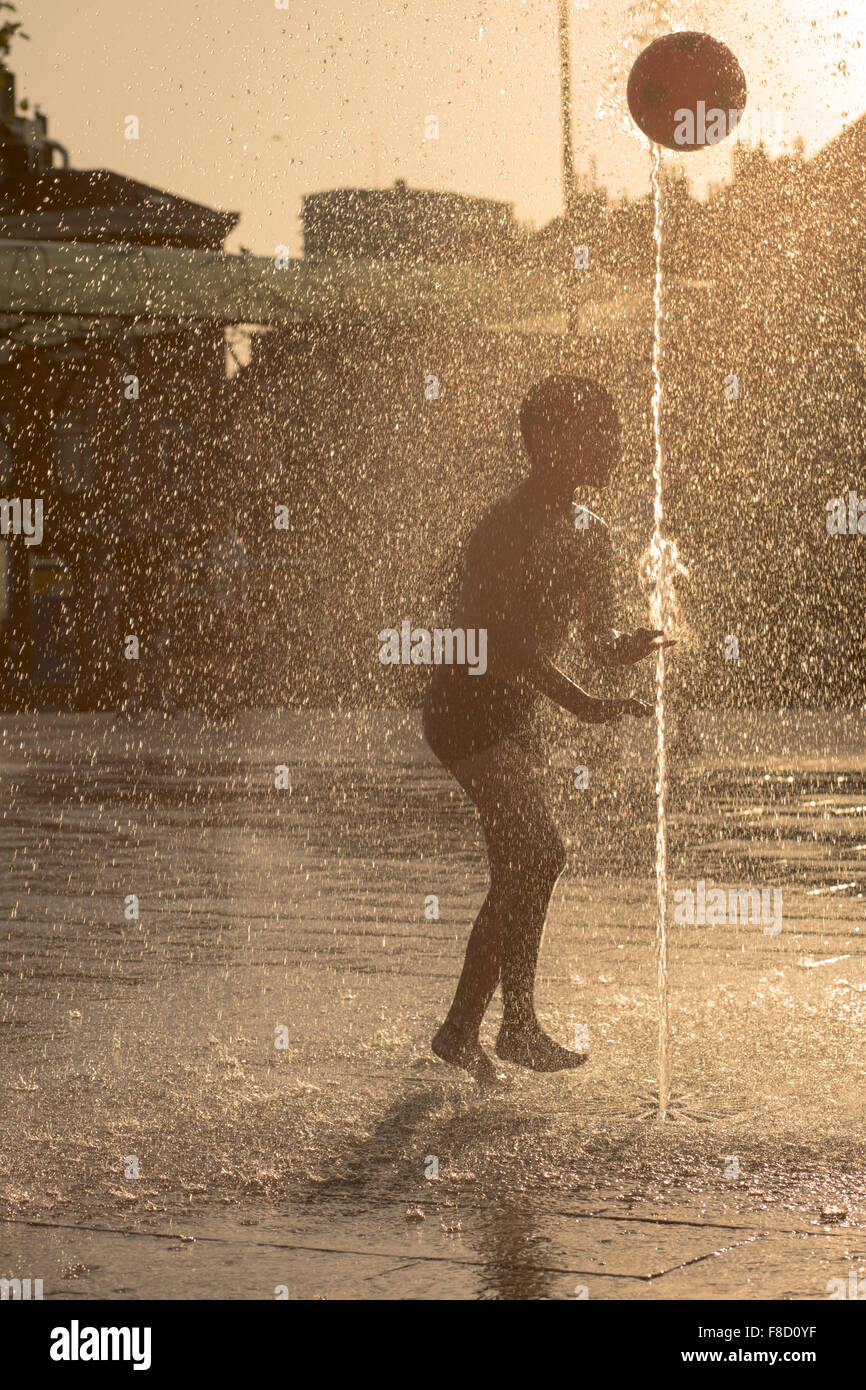Silhouette of a kid playing in a sunny water fountain Stock Photo - Alamy