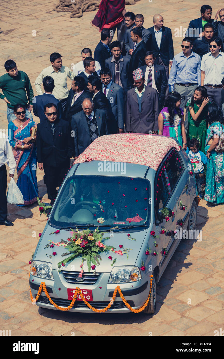 Group of people walking behind the lovers car at a public wedding in Nepal Stock Photo