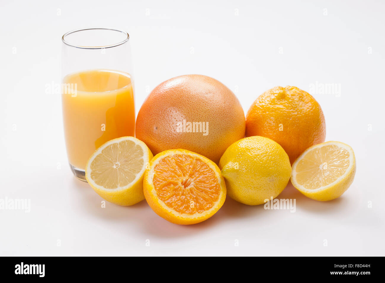 Orange and yellow color of fruits including grapefruit, orange, lemons with a glass of juice in orange color Stock Photo