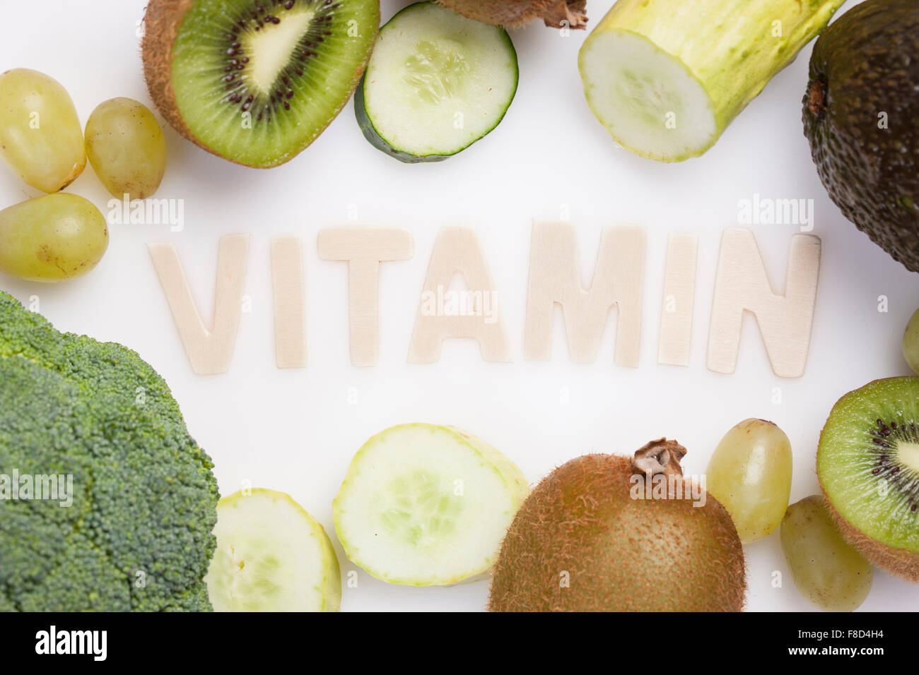 Solid word VITAMIN surrounded by green color of vegetables and fruits Stock Photo