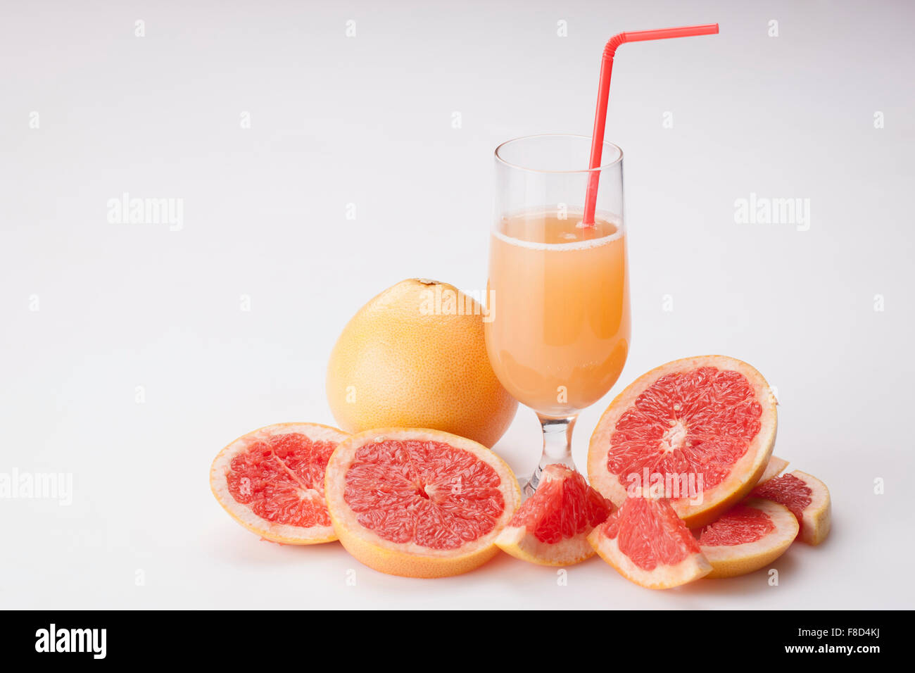 Glass of grapefruit juice with a straw in it in the middle of slices of grapefruits and a whole fresh grapefruit Stock Photo