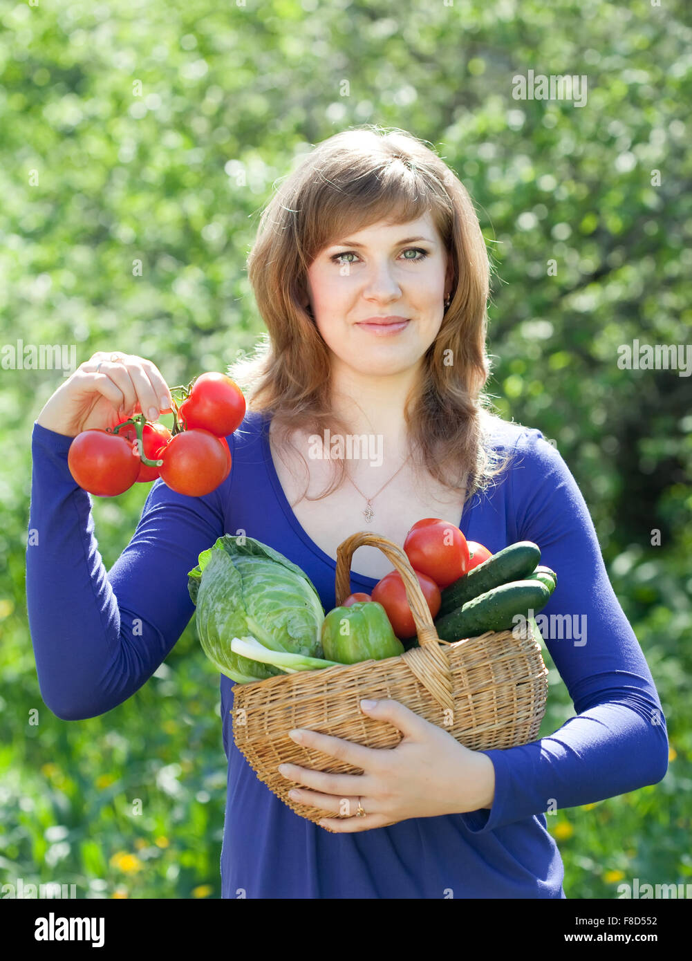 Happy young woman with basket of harvested vegetables in garden Stock ...
