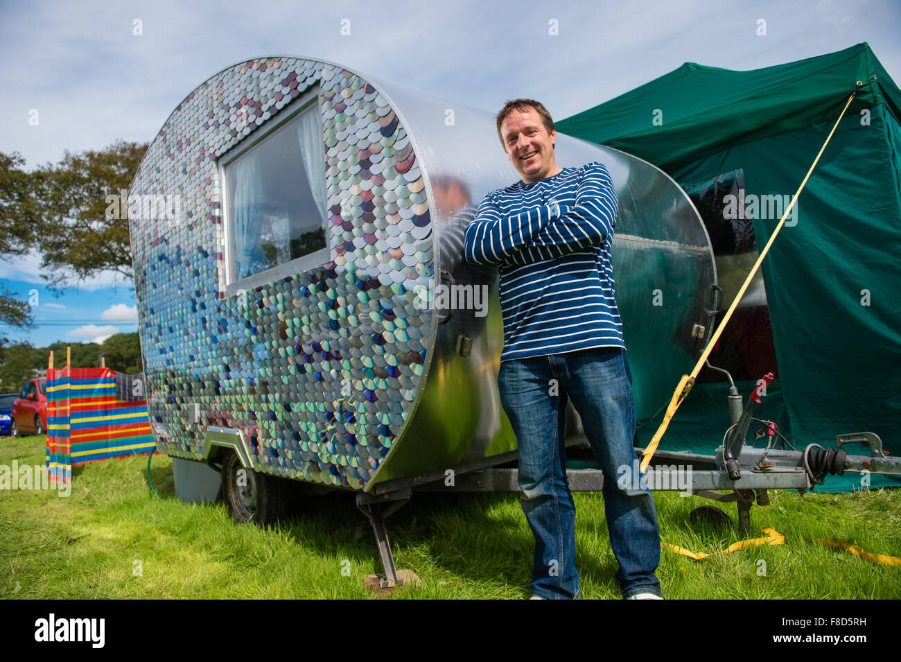 Craftsman and maker Carwyn Lloyd Jones, standing outside  his small wooden-framed caravan which he made himself from salvaged scrap  timber and covered on the outside with recycled compact discs, Aberystwyth Wales UK Stock Photo