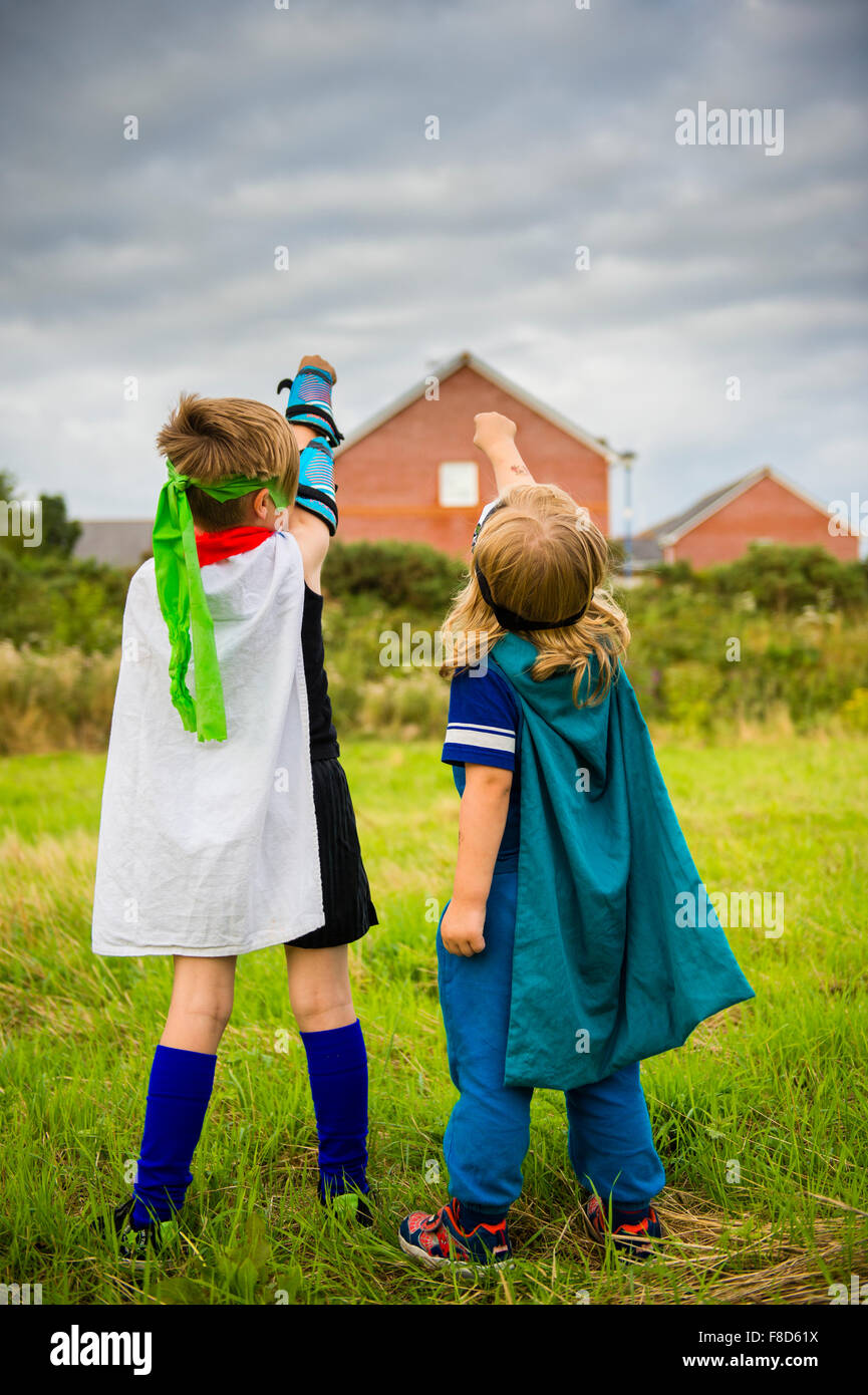 Two boys in home made costumes dressed up and playing outdoors at being Mini Superheroes  on a summer evening , UK Stock Photo