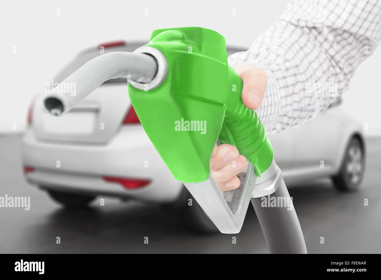 Green color fuel pump gun in hand with car on background Stock Photo