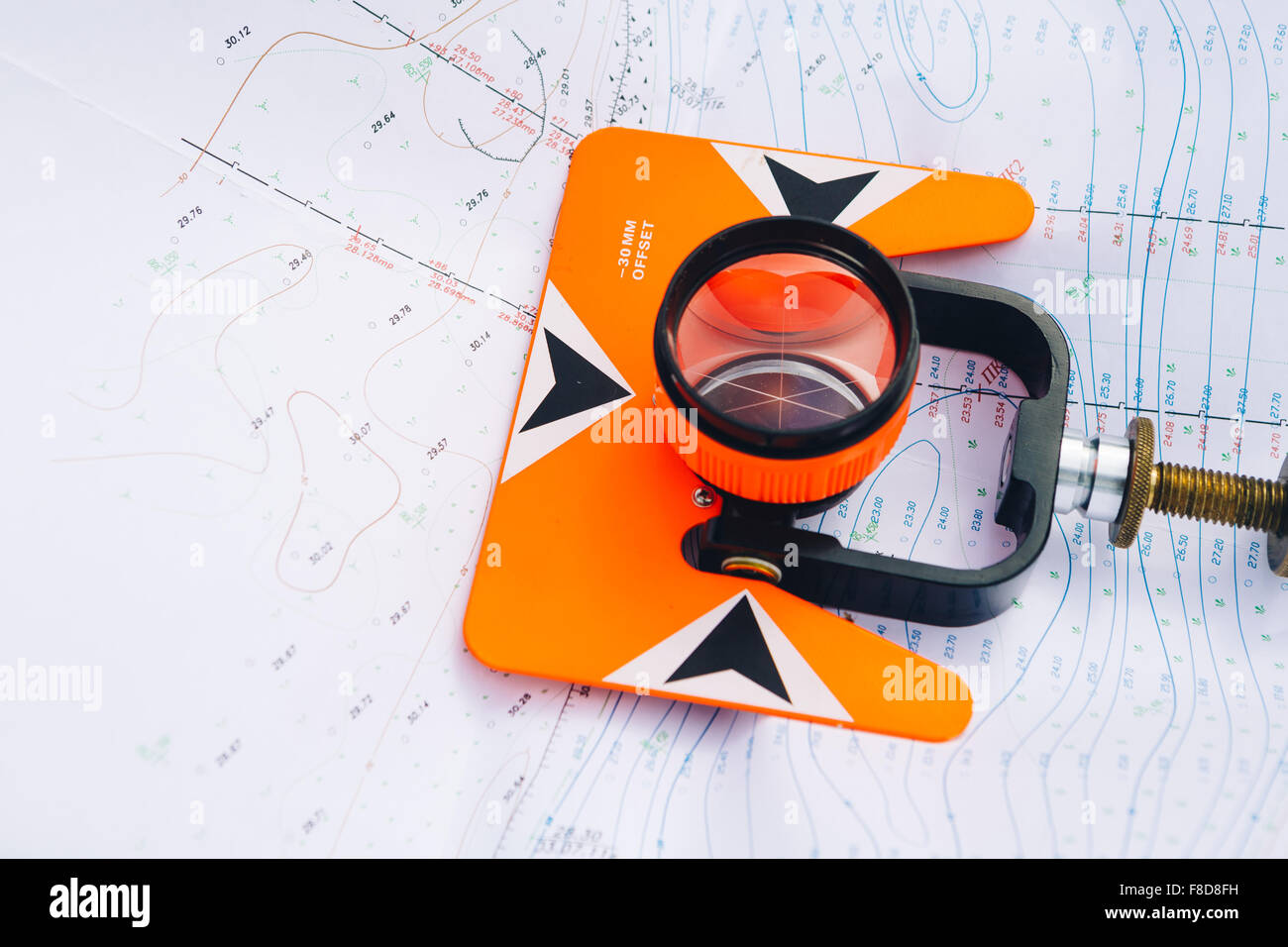 orange theodolite prism  lies on a background of geodetic maps of the area Stock Photo