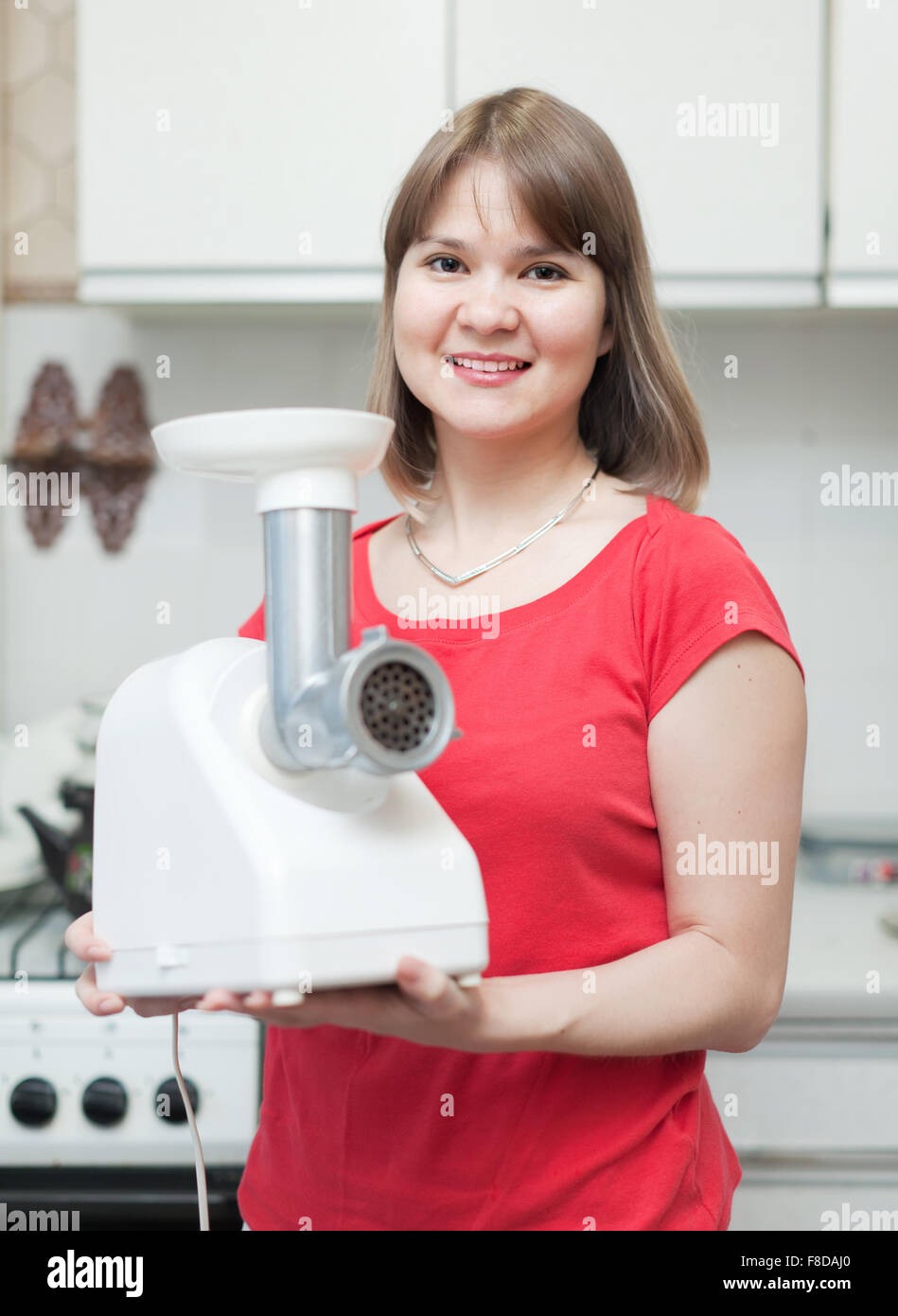 Young woman with electric grinder at home Stock Photo